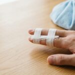Hand with a jammed index finger buddy taped to the middle finger on a clean white background