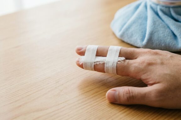 Hand with a jammed index finger buddy taped to the middle finger on a clean white background