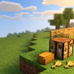 A Minecraft crafting table sits on a grassy hillside next to a single loaf of bread and three pieces of wheat floating as items on the ground. In the background, a small fenced-in farm is visible, filled with fully grown, golden wheat ready for harvest under a bright, sunny blue sky with soft clouds.