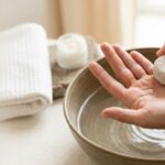 A close-up shot focuses on a person's hands over a ceramic bowl filled with water.