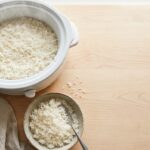 Bowl of fluffy white rice next to an open slow cooker on a kitchen counter