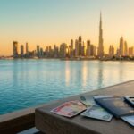 Dubai skyline with the Burj Khalifa at sunset, with a travel budget calculator and passport in the foreground